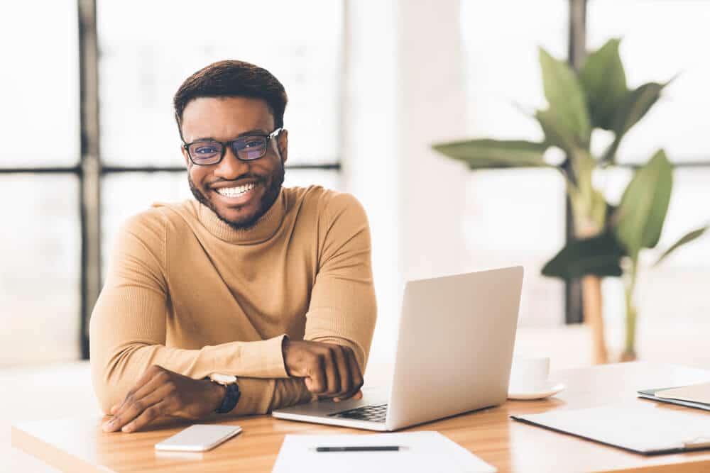 man smiling from behind laptop