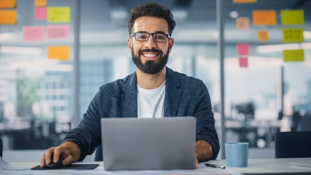 Man smiling while working on a laptop